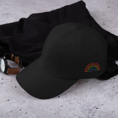 black baseball dad hat with multicolored pride rainbow embroidered on the left of the hat amongst other clothing items