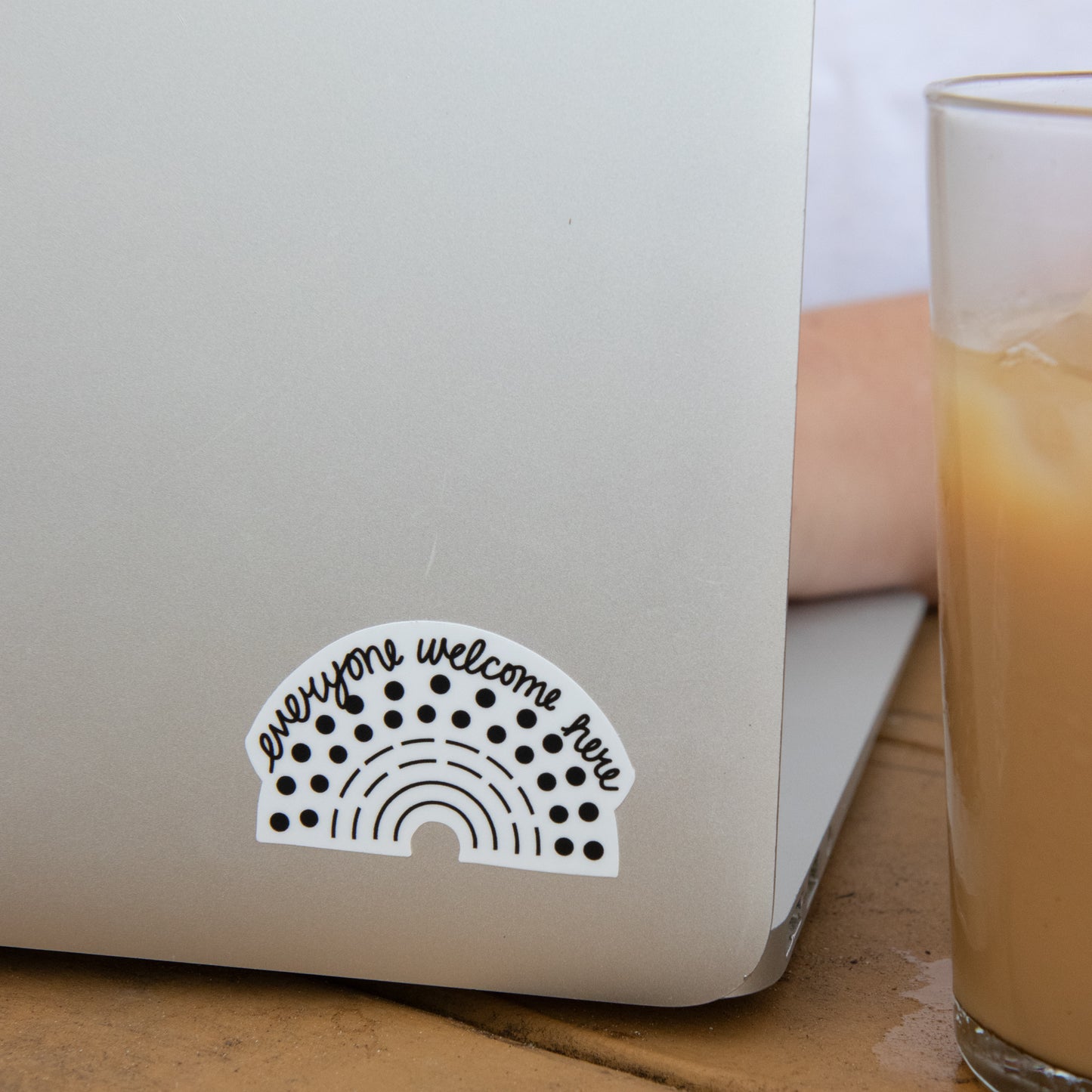 Zoomed in image of a laptop with a black pride sticker with the phrase everyone welcome here