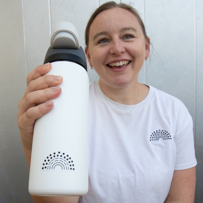 Person holding a water bottle with a black pride sticker