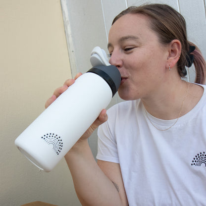 Person holding a water bottle with a black pride sticker