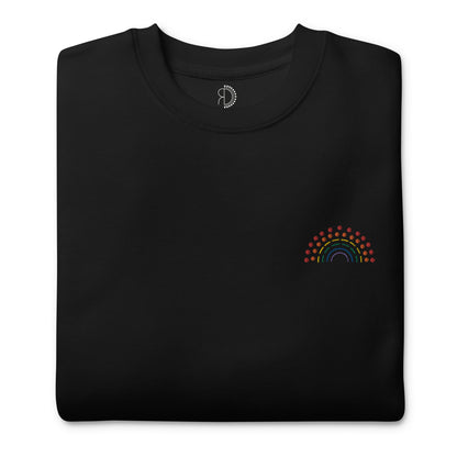 folded black crewneck sweatshirt with multicolored pride rainbow embroidered on the left chest and an inside label featuring logo