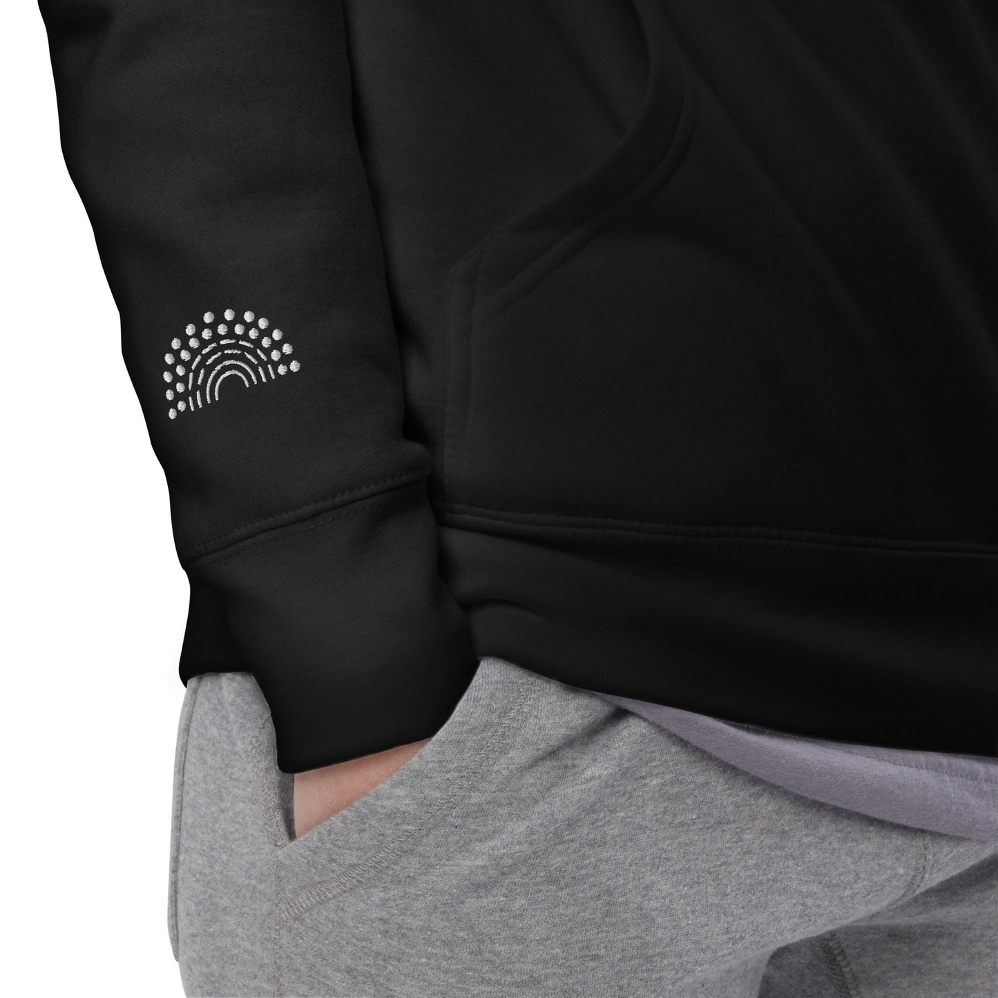 zoomed in image of person wearing a black crewneck sweatshirt with white pride rainbow embroidered on the right wrist