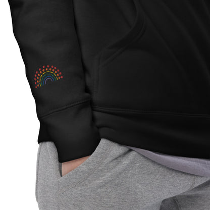 zoomed in image of person wearing a black hoodie sweatshirt with multicolored pride rainbow embroidered on the right wrist