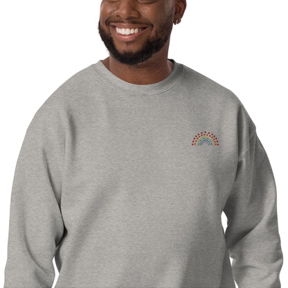 zoomed in image of person wearing a grey crewneck sweatshirt with multicolored pride rainbow embroidered on the left chest