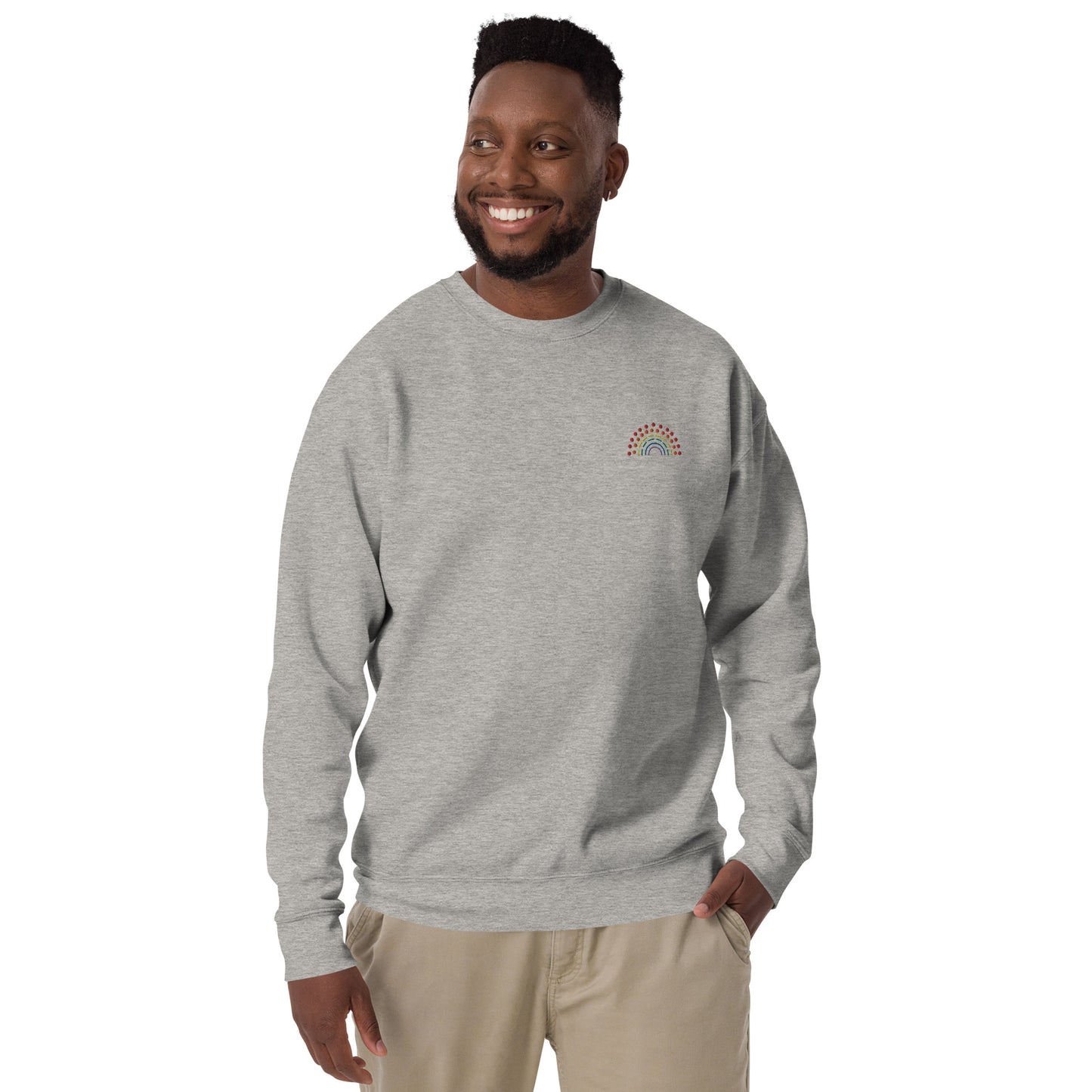 person wearing a grey crewneck sweatshirt with multicolored pride rainbow embroidered on the left chest