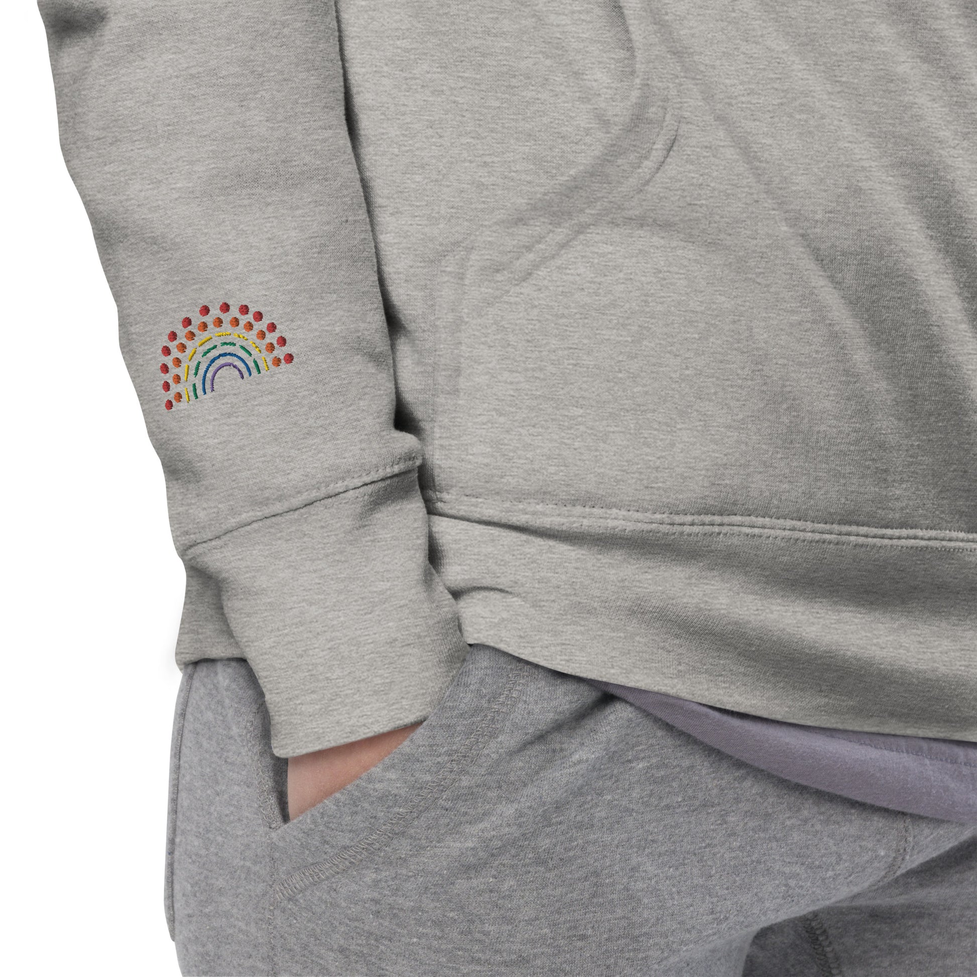 zoomed in image of person wearing a grey crewneck sweatshirt with multicolored pride rainbow embroidered on the right wrist