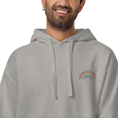 person wearing a grey hoodie sweatshirt with multicolored pride rainbow embroidered on the left chest