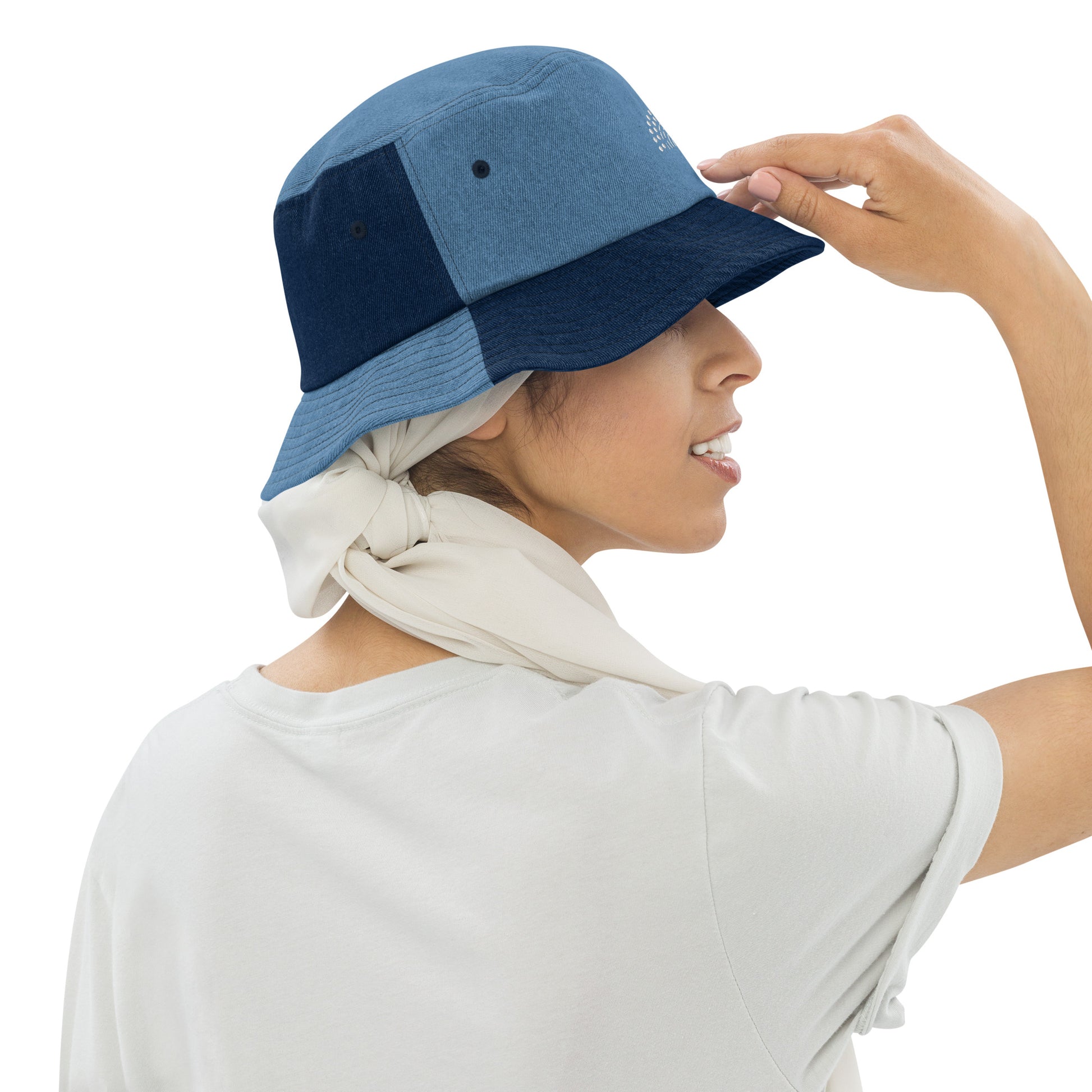 person wearing a mixed denim bucket hat with white pride rainbow embroidered on center of the hat