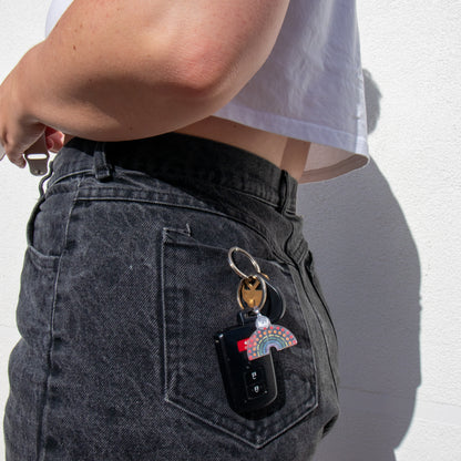 Car keys and multicolored pride keychain in the back pocket of a person