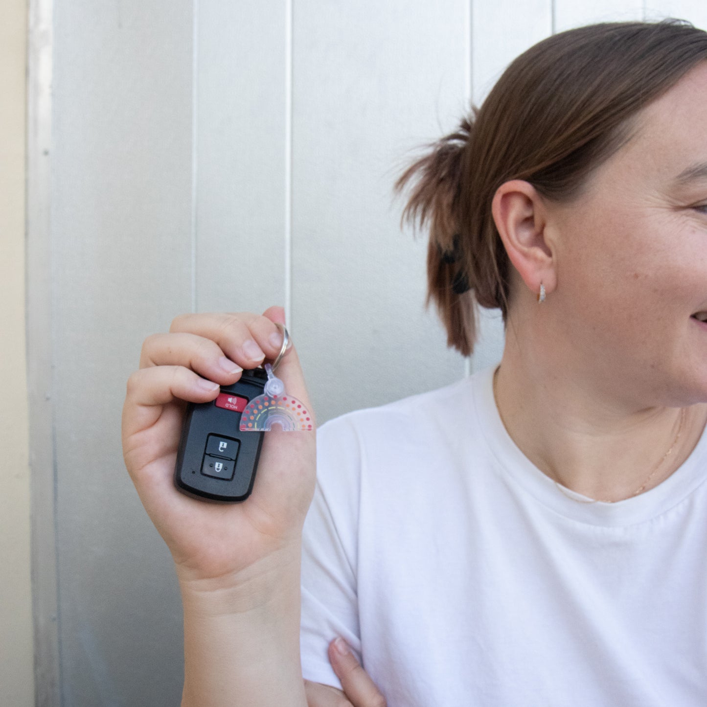 Person holding car keys with multicolored pride keychain