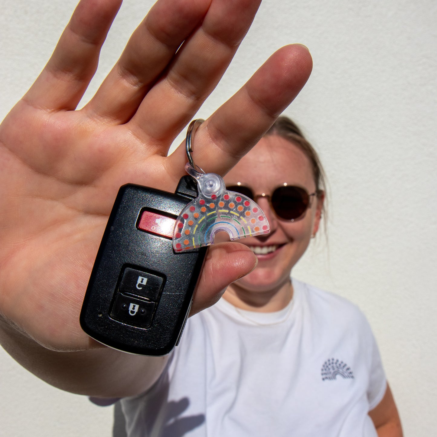 Person holding car keys with multicolored pride keychain