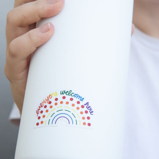 Zoomed in image of a water bottle with a multicolored pride sticker with the phrase everyone welcome here