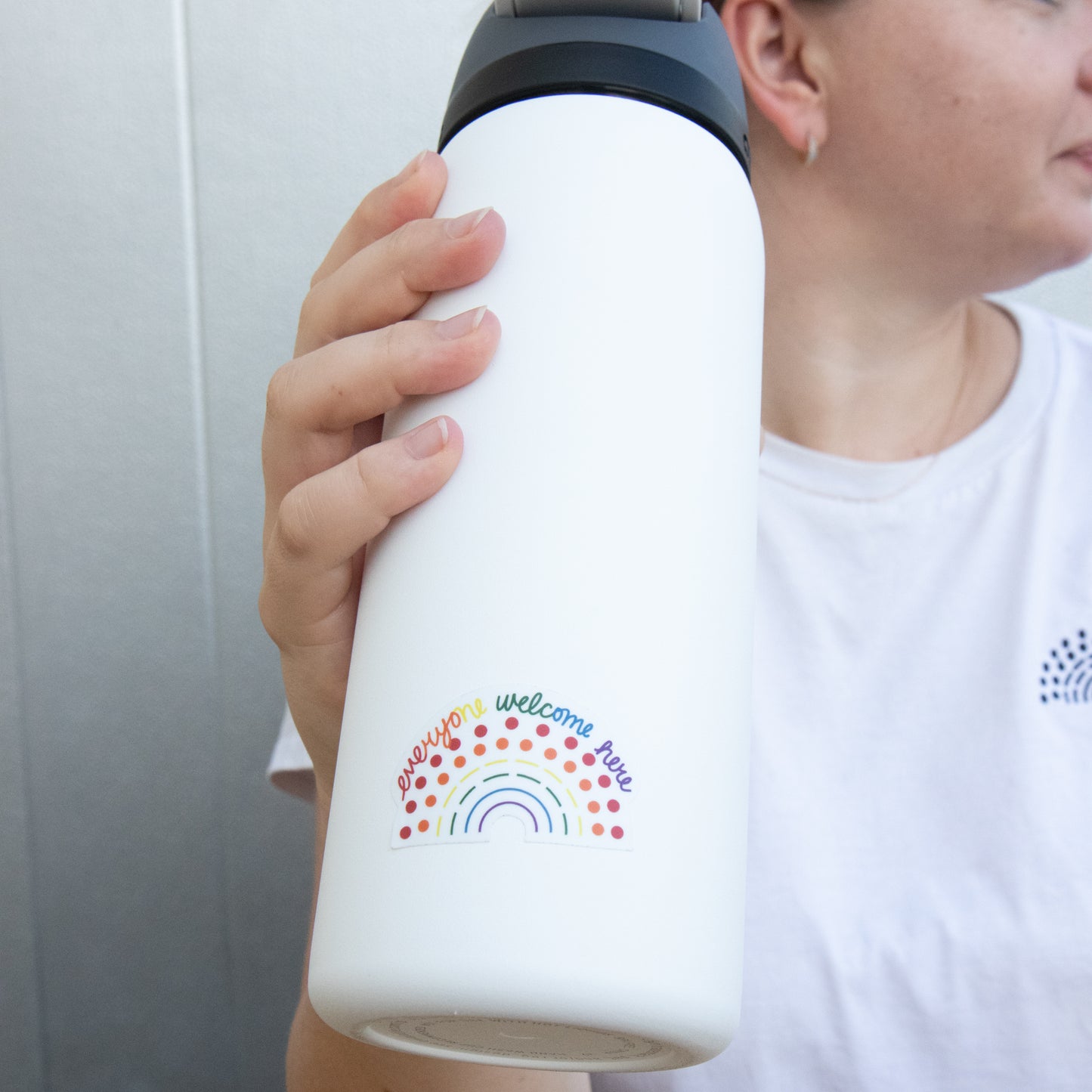 Zoomed in image of a water bottle with a multicolored pride sticker with the phrase everyone welcome here