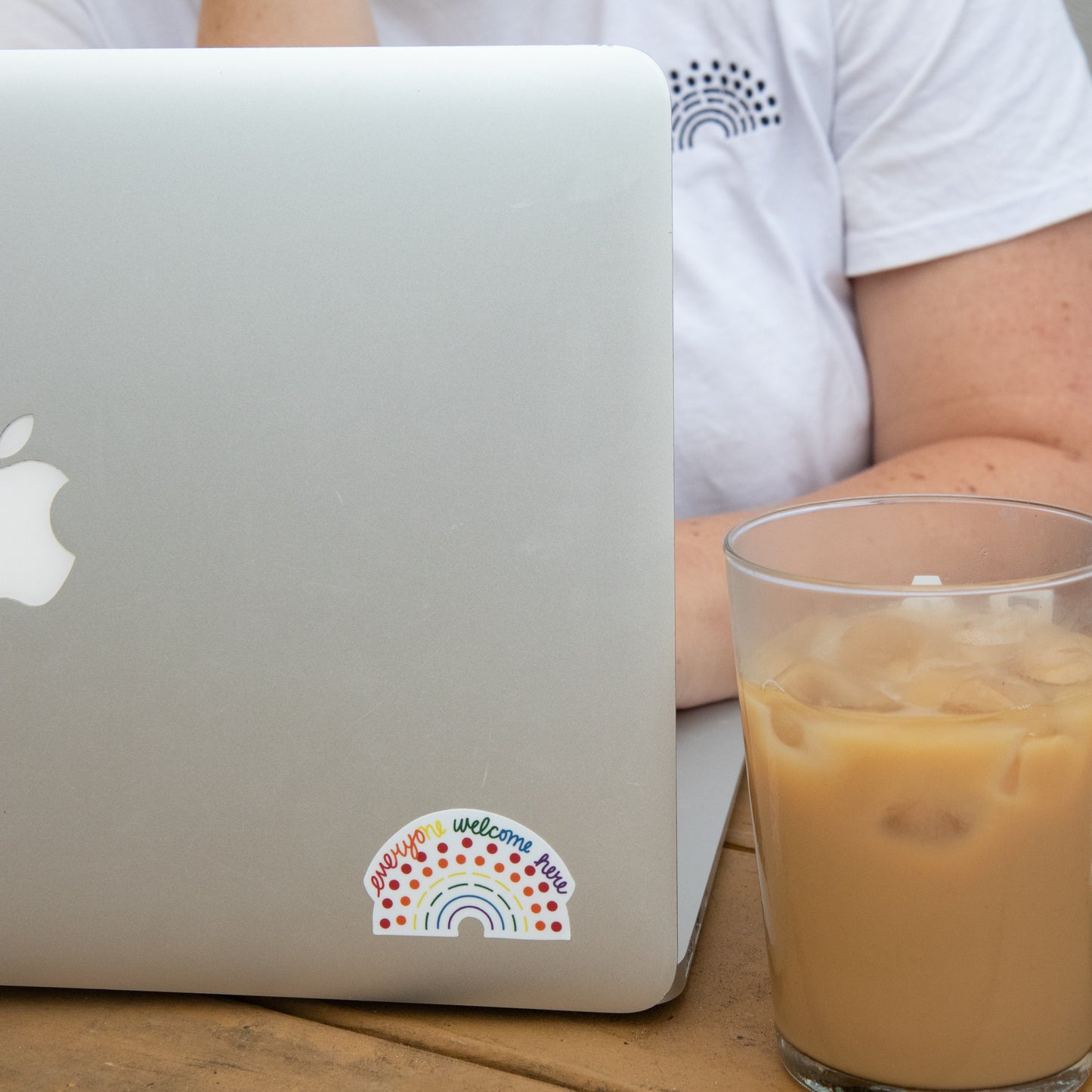 Zoomed in image of a laptop with a multicolored pride sticker with the phrase everyone welcome here