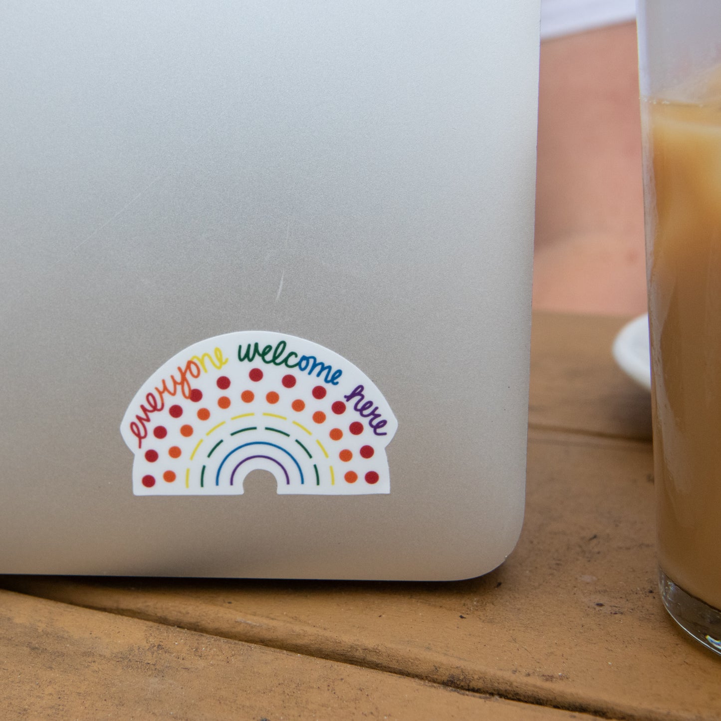 Zoomed in image of a laptop with a multicolored pride sticker with the phrase everyone welcome here