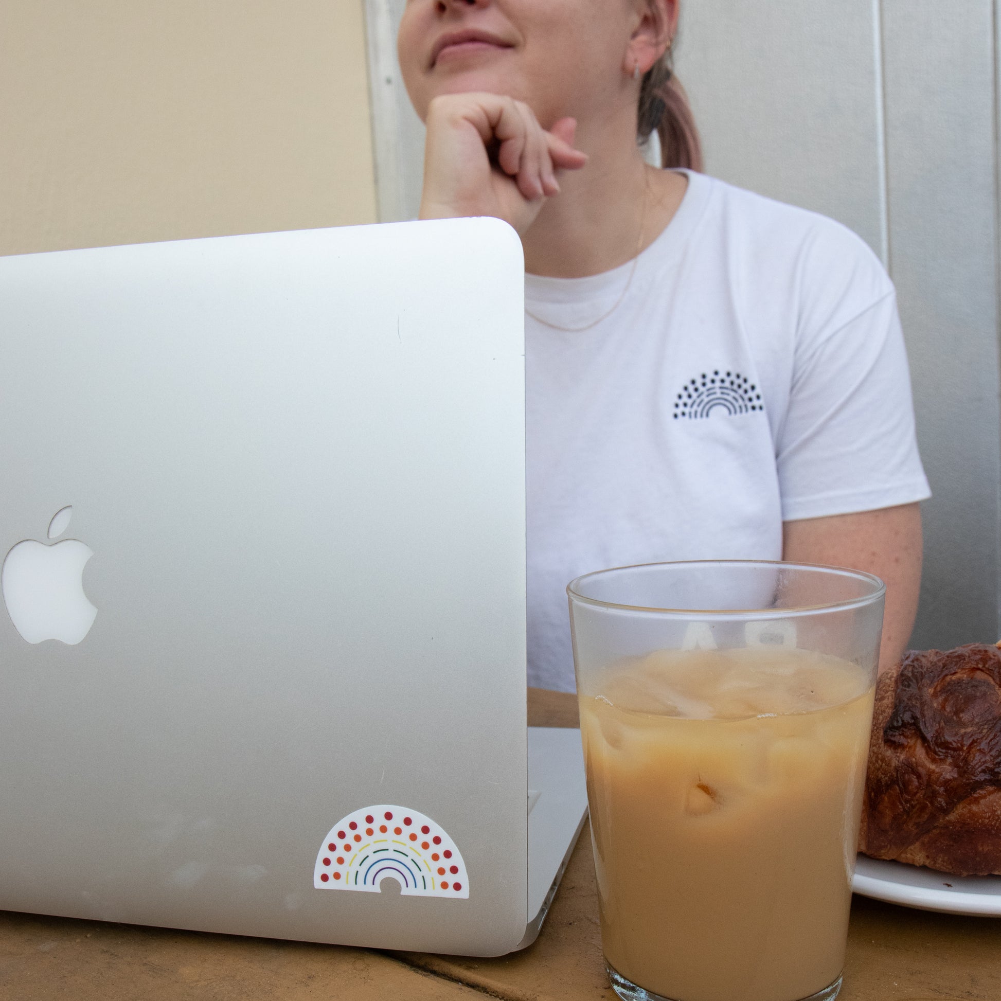 Person working on a laptop with a multicolored pride sticker