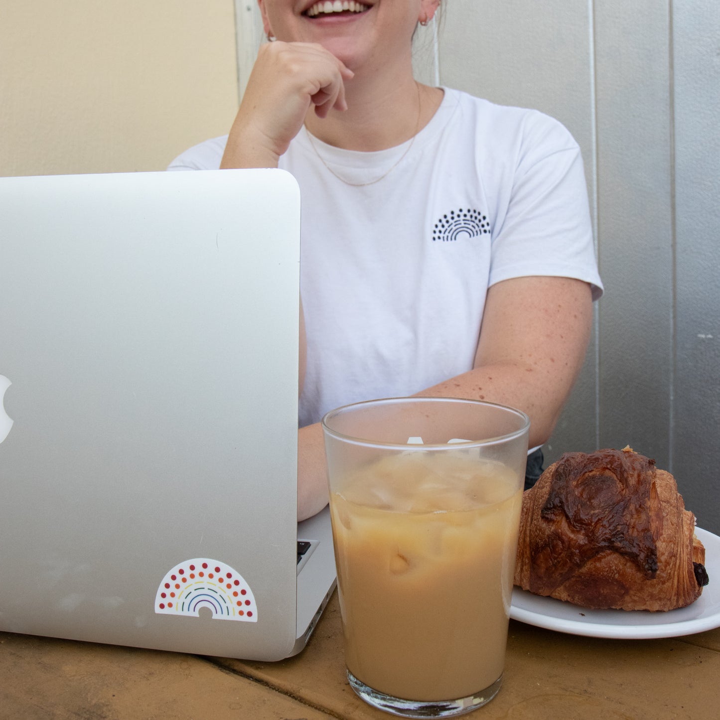 Person working on a laptop with a multicolored pride sticker