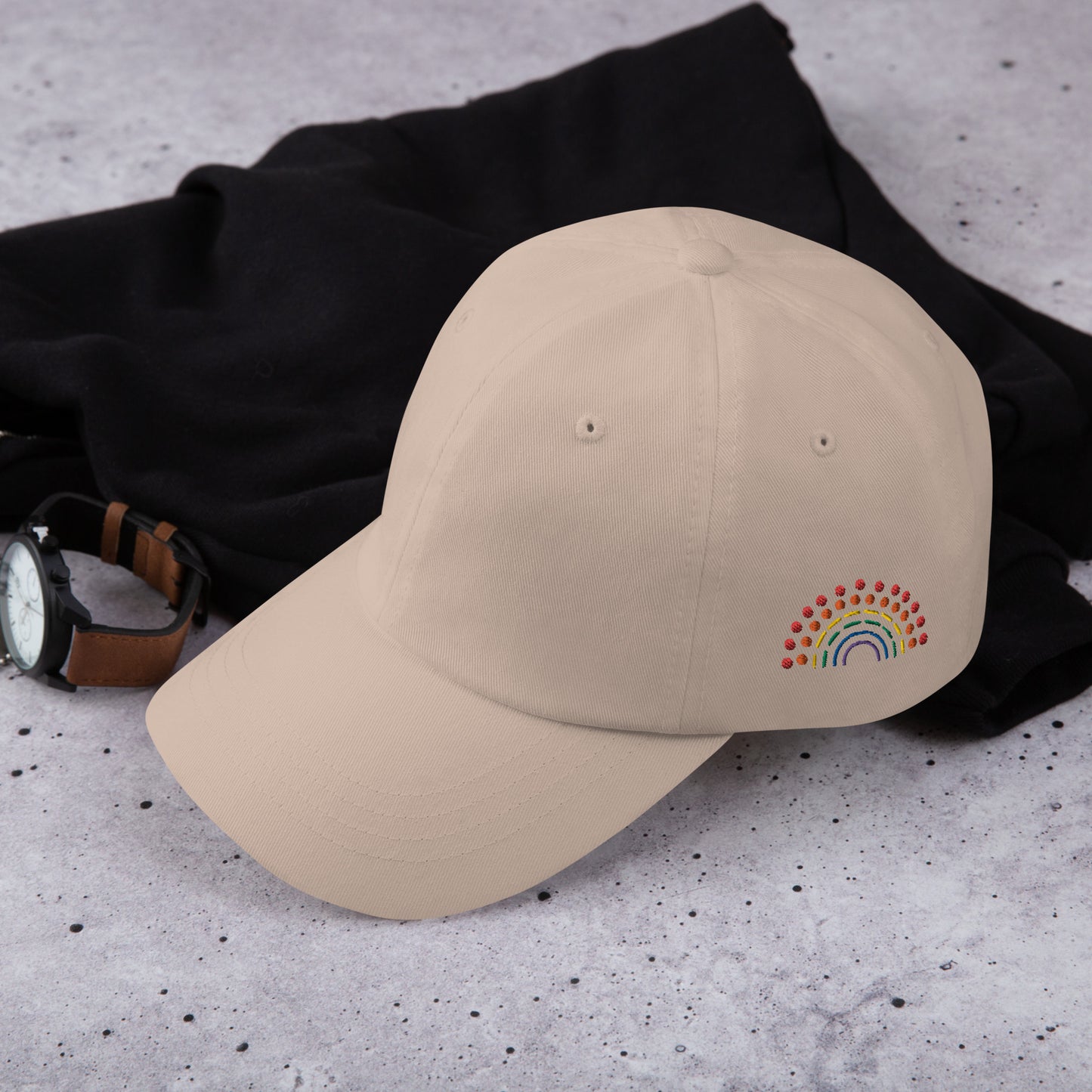 stone tan baseball dad hat with multicolored pride rainbow embroidered on the left of the hat amongst other clothing items